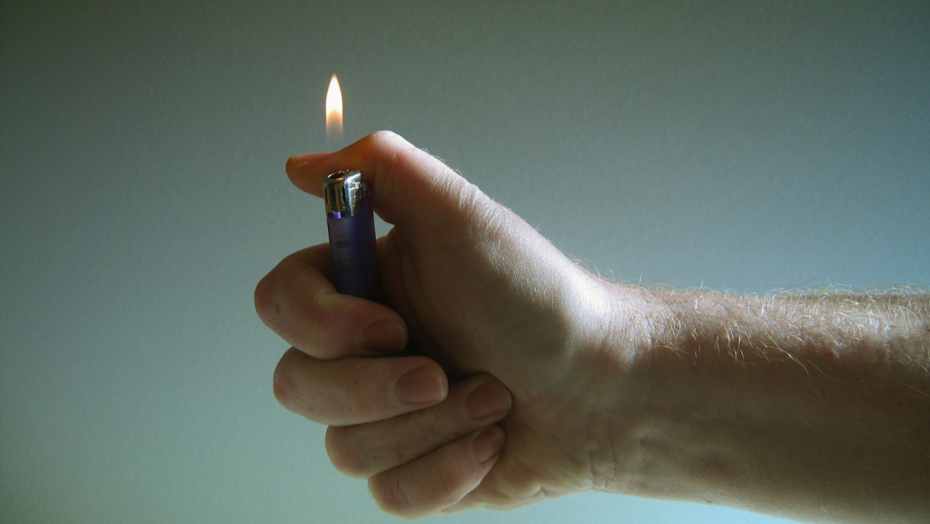 A hand holding a lit lighter 